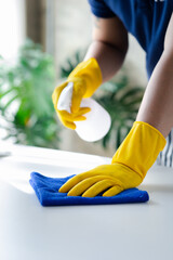 Person cleaning the room, cleaning staff is using cloth and spraying disinfectant to wipe the...