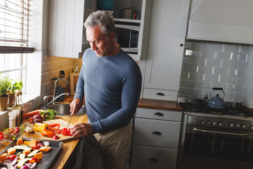Happy caucasian man standing in kitchen and cooking dinner
