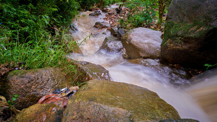 Naklejka na ściany i meble Small waterfall, water flow in a mountainous area, Bogor, Indonesia