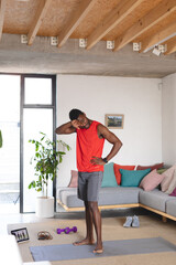 Fototapeta na wymiar Happy african american man exercising, using tablet in living room