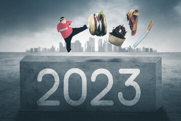 Fat man kick junk foods on stone with 2023 number