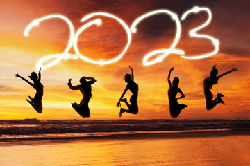 Group of women jump with 2023 number on beach