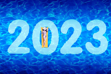 Woman lying on inflatable float with 2023 number