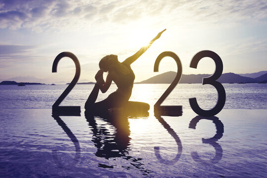 Woman practice yoga with 2023 numbers on beach
