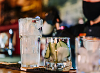hands of a bartender with black gloves making cocktail on a bar counter.