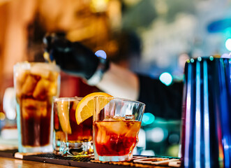 hands of a bartender with black gloves making cocktail on a bar counter.