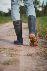 farmer wears boots walking on the path, farming concept, cultivation and agriculture