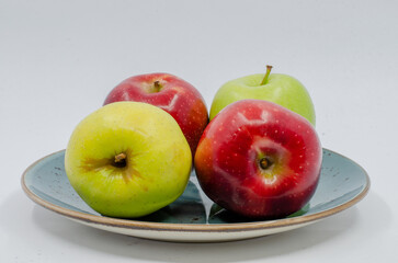 Red and Green colored Apples in a blue colored plate. Red and green apples isolated on a white background.
