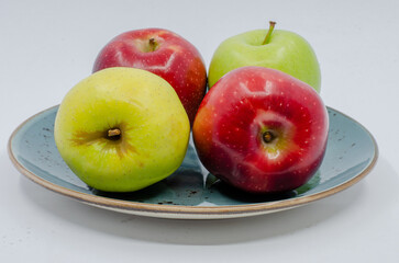 Red and Green colored Apples in a blue colored plate. Red and green apples isolated on a white background.
