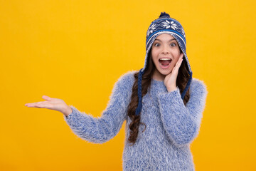 Fashion happy young woman in knitted hat and sweater having fun over colorful blue background. Excited teenager girl.