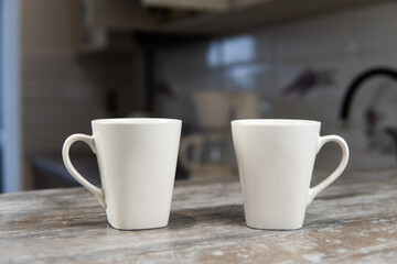 two white mugs stand in the kitchen