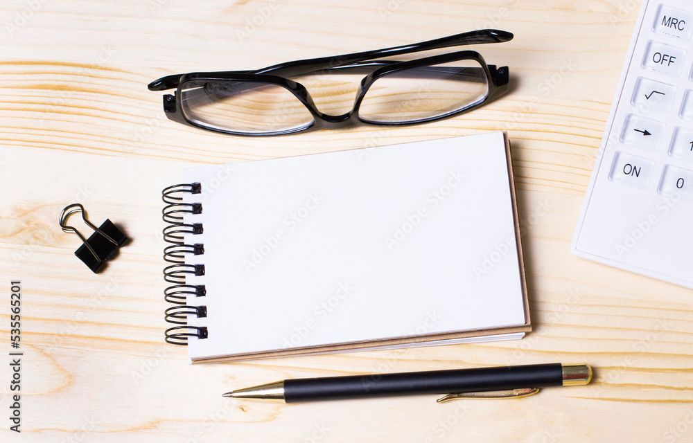 Poster a clean notebook with a pen is lying on a wooden office table. top view with copy space, flat layout