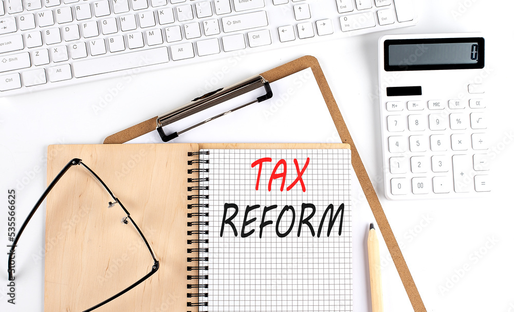 Poster notebook with the word tax reform with keyboard and calculator on the white background