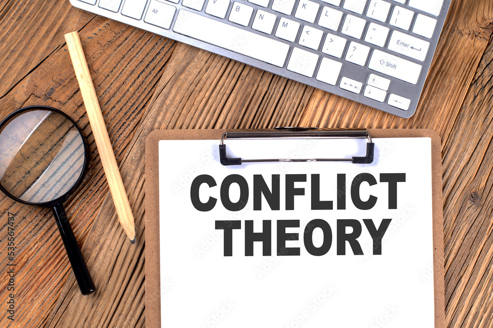 Poster conflict theory text on paper clipboard with magnifier and keyboard on wooden background
