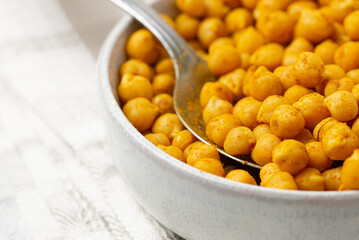 Indian traditional dish crispy roasted chickpeas with spices  on a white plate with spoon, selective focus, low depth of field