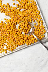 Roasted chickpeas covered with curry powder with spoon on pan. Flat lay, top view