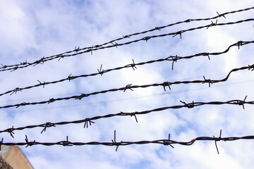 Barbed wire on a background of white-blue sky