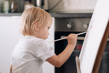 Child drawing on the easel. The hand and paint brush. Closeup, selective focus. Child is painting with paintbrush