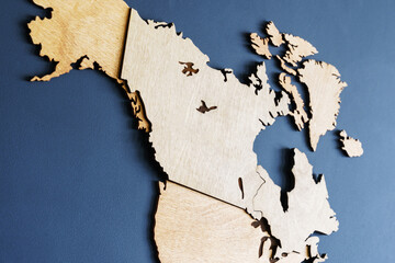 A wooden map of the world on a dark wall. Close-up of Canada and America.