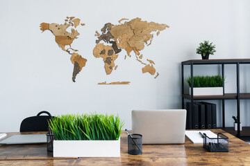 A wooden map hangs on a light wall in the office. A world map in a stylish interior. © makedonski2015