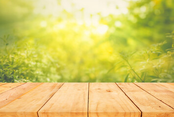 Selective focus of wood table top on blur green of tree background.