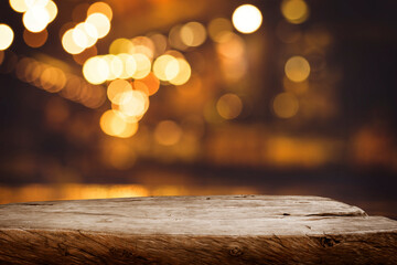 Selective focus.Wood table top with blur light bokeh in dark night cafe,restaurant background.