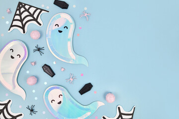 Cute pastel colored Halloween party flat lay with ghost shaped plates, spider web napkins and...