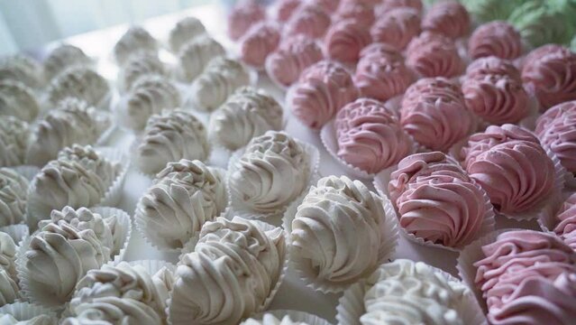Many red, green and white cooked marshmallows lie on the table. Camera rotating