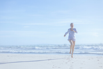 Full length portrait of smiling elegant female at beach running