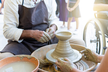 Potters working to shape the clay on the spinning wheel in the workshop. Tanned hands