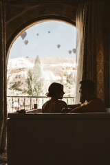 Couple taking a bath in the hotel in front of a window with hot air balloons flying in the background of the landscape - Cappadocia, Turkey