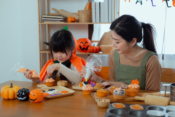 Happy halloween holiday, mother and daughter getting ready for holiday and baking cookies at home, Asian family,	