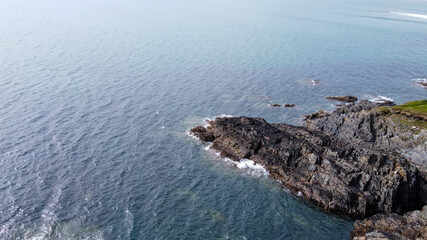 A large stone cape among the waters of the Atlantic Ocean, top view. Calm sea surface, seascape. Aerial photo.