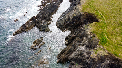 Nature on the Wild Atlantic Way, Ireland. Picturesque coastal cliffs on the shore of the Celtic Sea.  Rocky hills covered with thick green grass. Northern European landscape. Drone point of view.