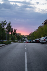 beautiful sunset in Alcobendas , Spain. Over the urban road, setting sun behind the town full of trees..