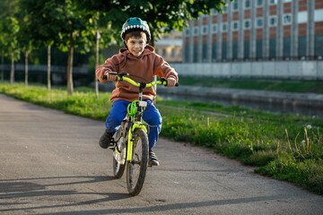 Fototapeta premium Boy learning to ride bike. Child travels through urban alley.