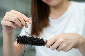 Asian woman have problem with long hair loss attach to comb brush.