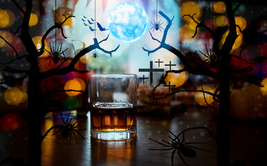 A glass of whiskey on wooden bar and halloween night background.
