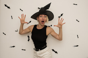 Halloween. Portrait of a witch. A beautiful woman in a witch hat with blonde hair screams and looks...