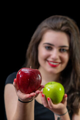 Szczęśliwa uśmiechnięta młoda dziewczyna proponuje zielone i czerwone jabłko - obrazy, fototapety, plakaty
