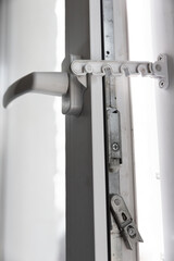 Close-up of a door latch with a latch in a double-glazed balcony frame. The concept of repairing doors and windows of the house