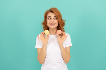 Fototapeta premium glad girl hold sweet macaron french cookie on blue background