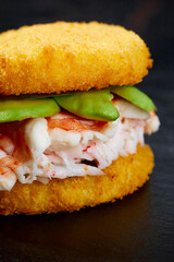 Pan-Asian cuisine concept. Japanese sushi burger made from rice bread, crab meat, avokado and wasabi sauce. Serving on wooden board. copy space