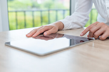 Digital tablet computer with a blank screen in the hands on wooden table