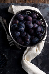 dramatic autumn still life with plums on a dark background. Rustic