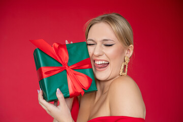 Happy cheerful woman in elegant red dress with evening makeup and hairstyle enjoy gift by closed...