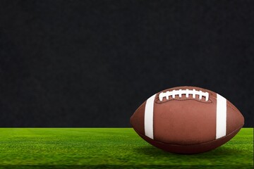 American Football ball on green field at the stadium