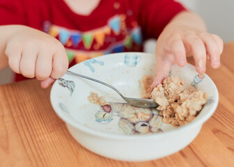 A boy is eating oatmeal for breakfast at the kitchen table