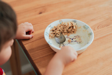 A boy is eating oatmeal for breakfast at the kitchen table