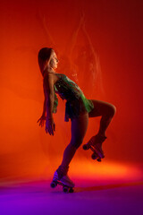 Fototapeta premium Dancing young mixed race girl enjoying moving in colorful neon studio light. Long exposure. woman dancing on roller skates, figure skating